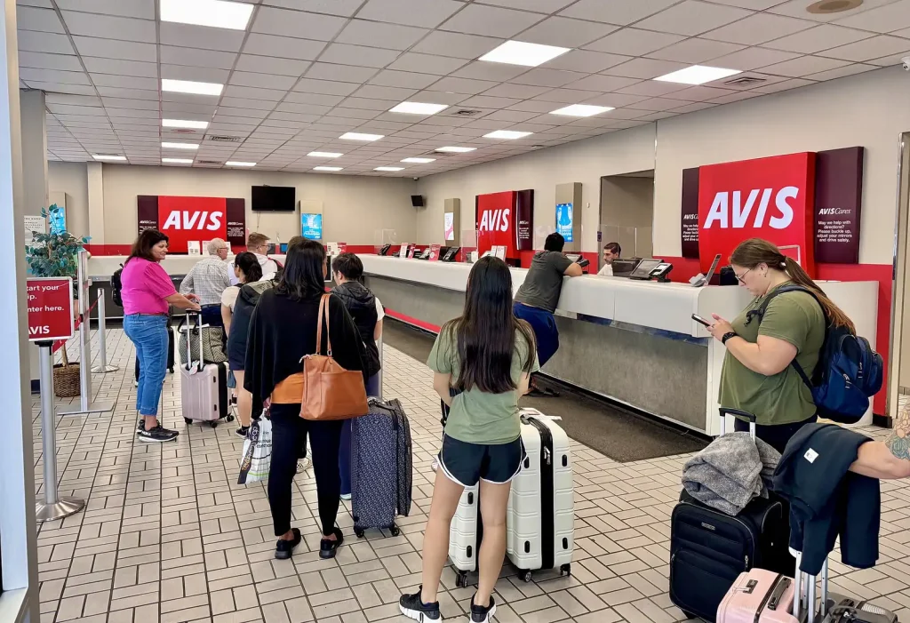 Travellers with luggage at airport car rental desks — Car Rental Booking Engines and Aggregators in the UAE
