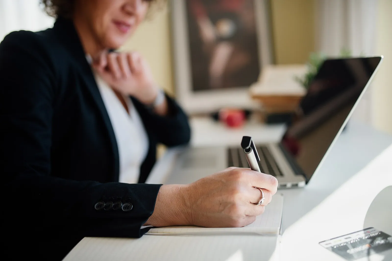 Business professional taking notes beside a laptop