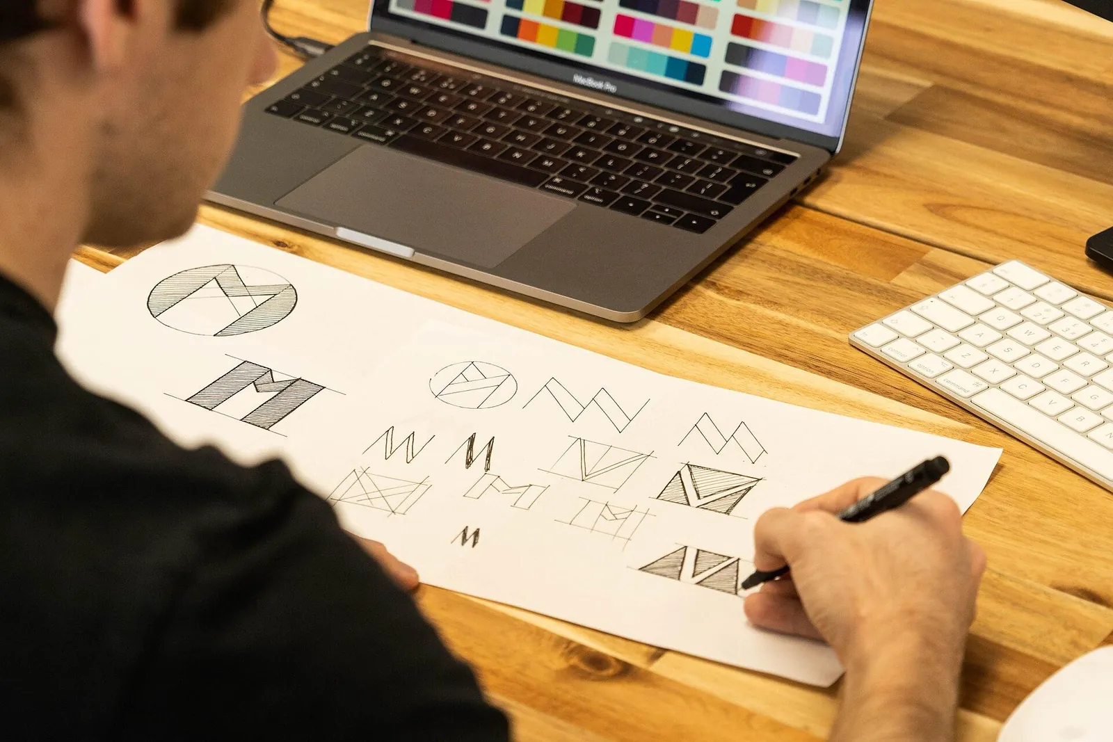 Logo design sketches and brand colour palette on a desk — brand identity uae