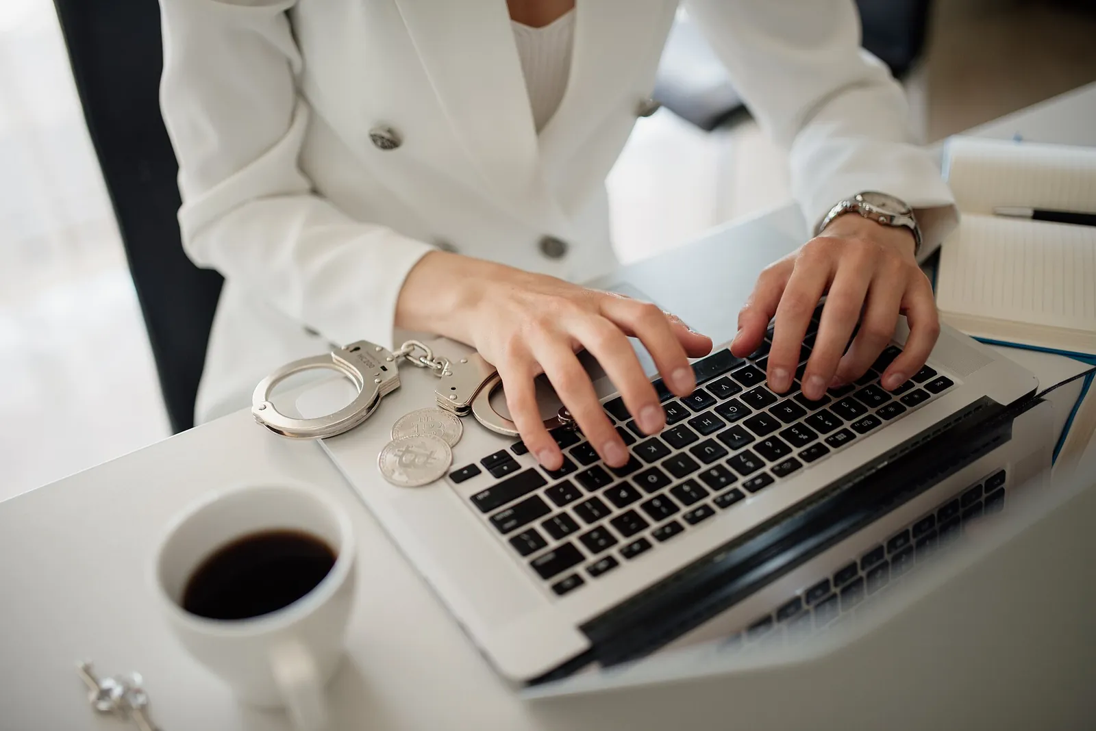 Hands typing on a laptop next to a coffee cup